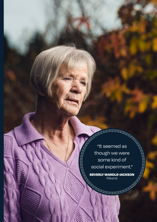 Beverly Wardle-Jackson stands in a garden with Autumn leaves on a tree behind her